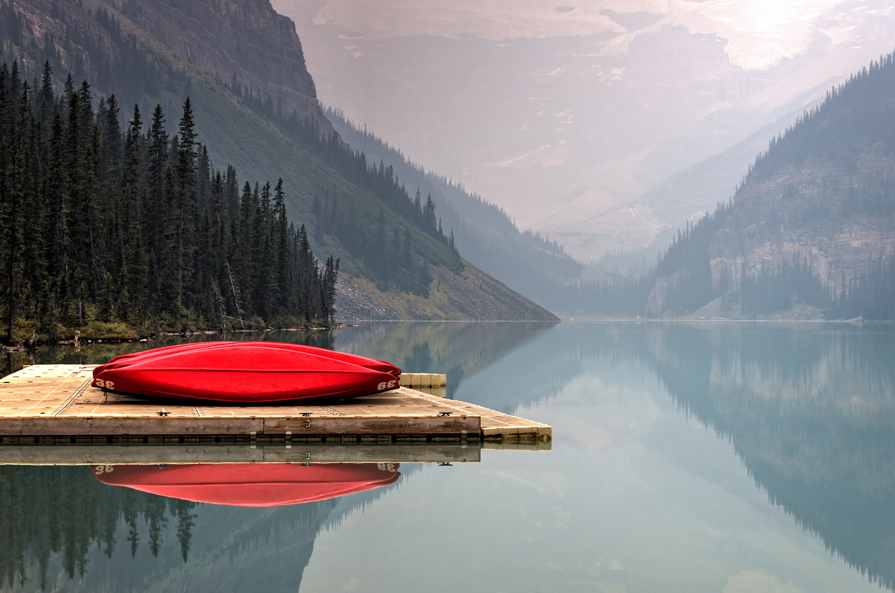 Still mountain lake reflecting the landscape beside a canoe dock