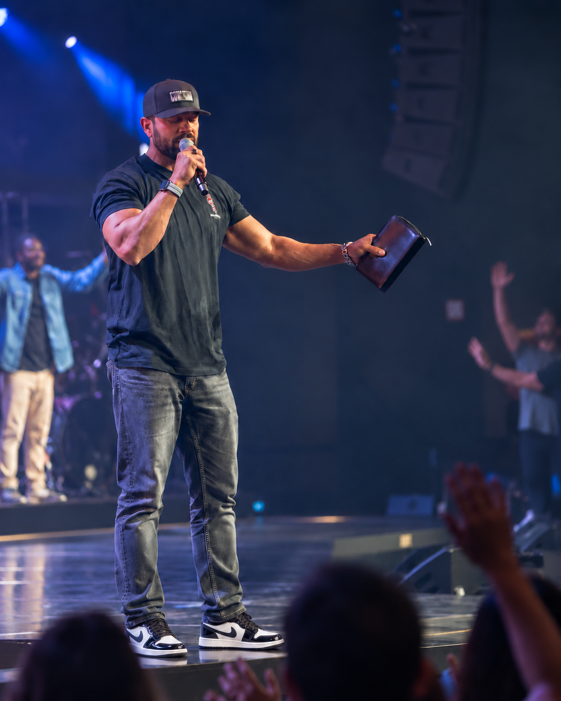 Jason Godinho praying over an event room while holding a Bible and microphone.