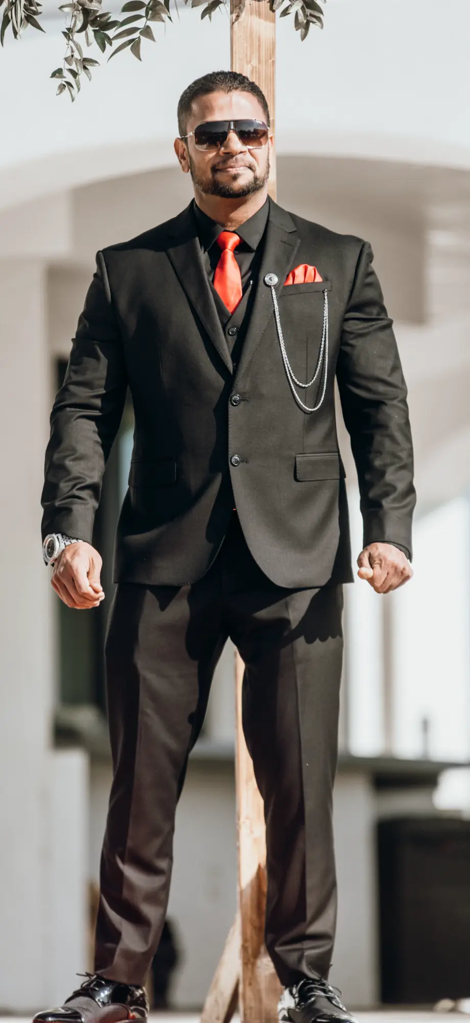 Full-length portrait of Jason Godinho in a black and red suit.